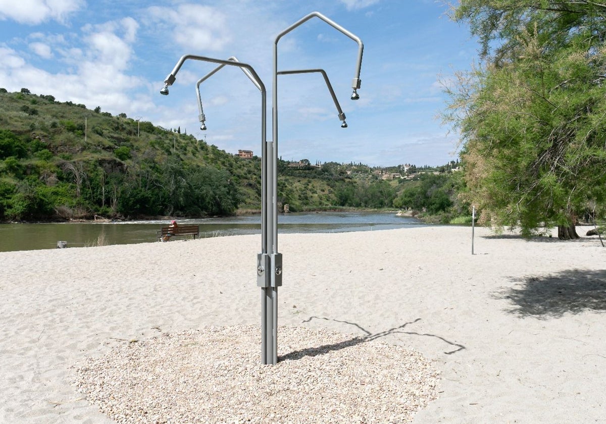 La nueva ducha instalada en la playa; detrás una mujer toma el sol sentada en un banco
