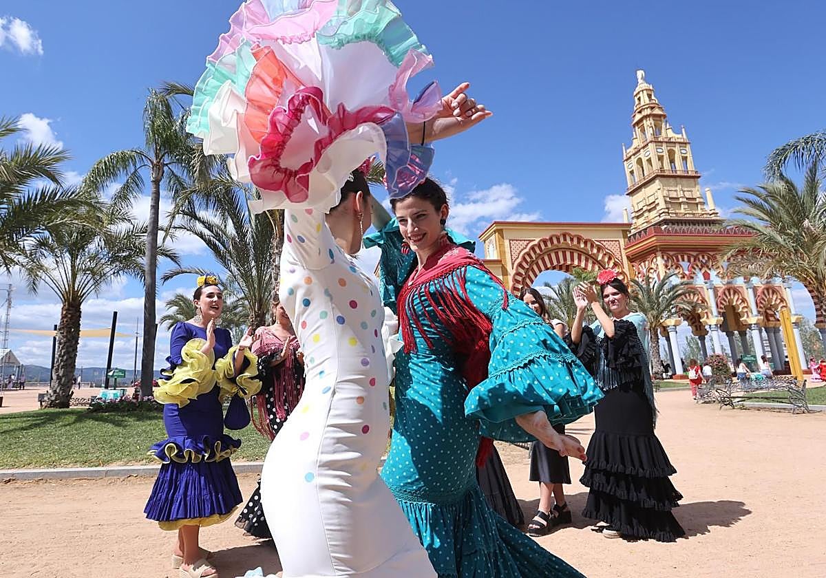 Un grupo de chicas bailando sevillanas ante la portada de la Feria de Córdoba