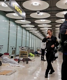 Imagen secundaria 2 - Indigentes pasan la noche en T4 de Barajas la madrugada de ayer; debajo, un trabajador recoge los carritos y una policía nacional en la planta 1