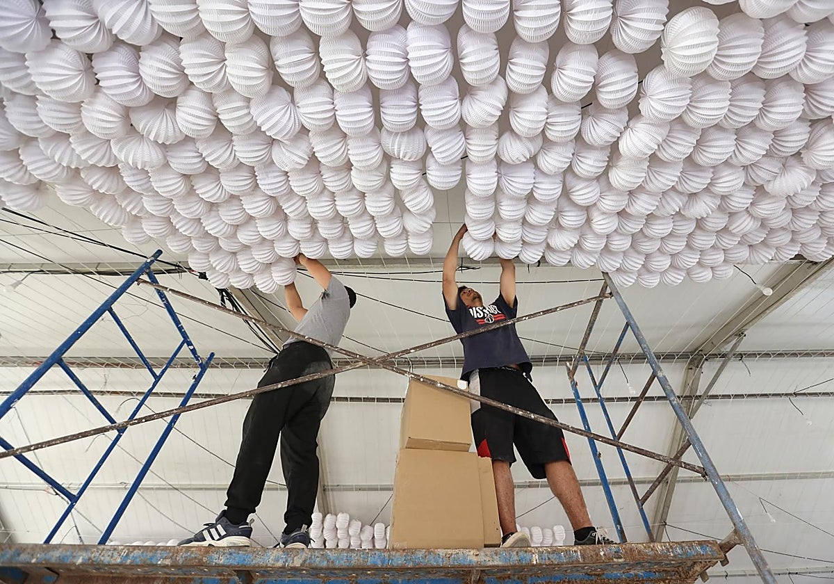 Dos operarios durante el montaje de una caseta en El Arenal este domingo en Córdoba