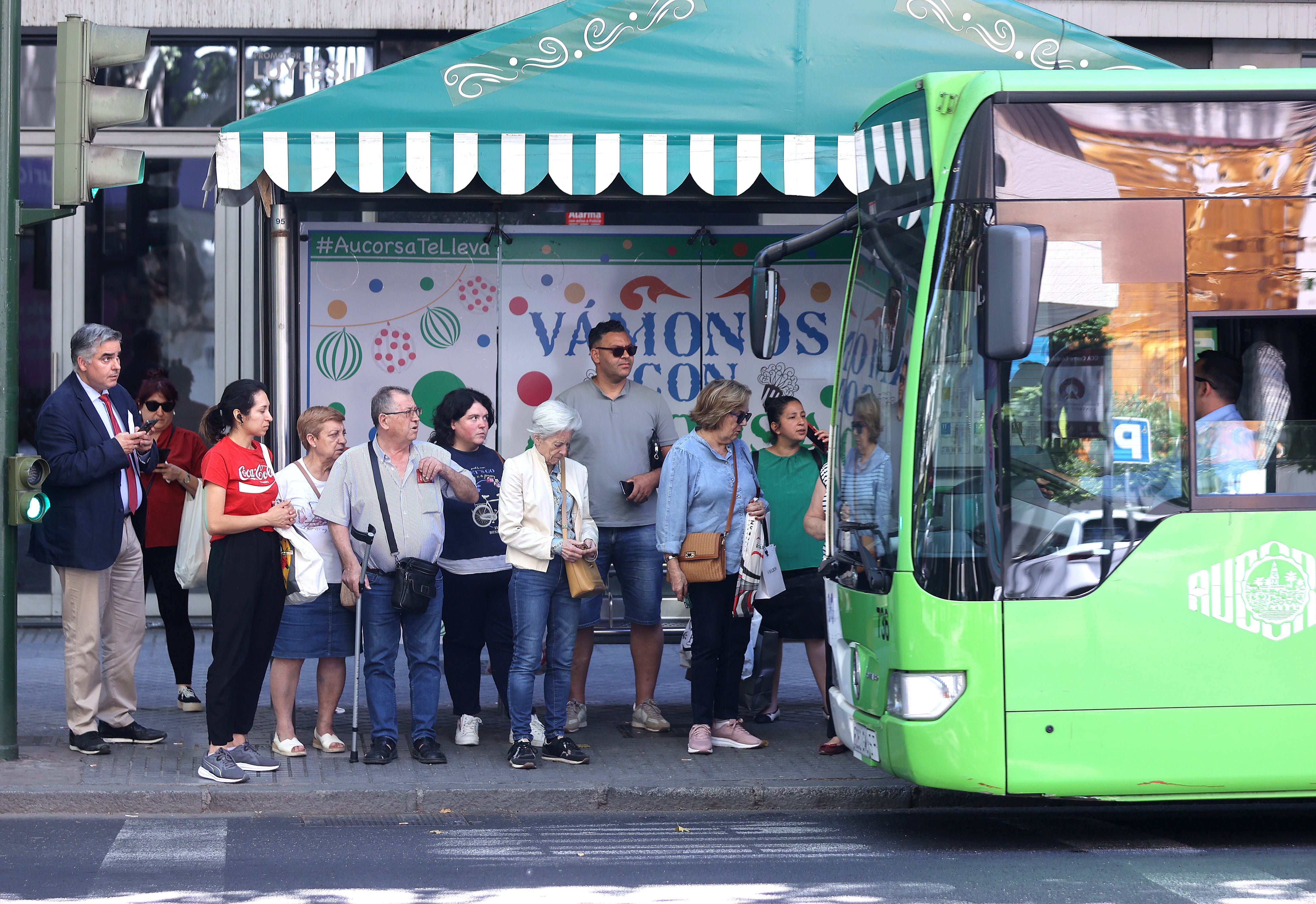 Varias personas esperan su autobús en una parada de Ronda de los Tejares