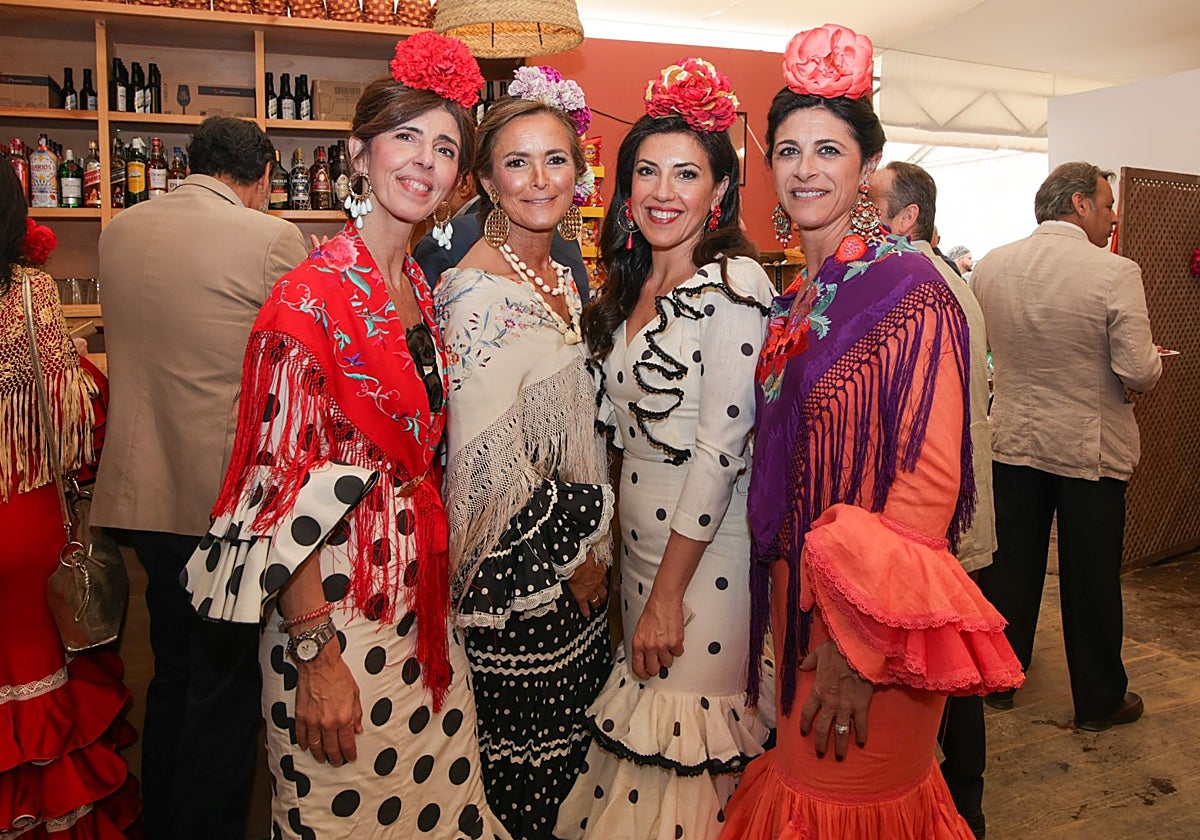 Cuatro mujeres vestidas de flamenca en una caseta de la Feria de Córdoba