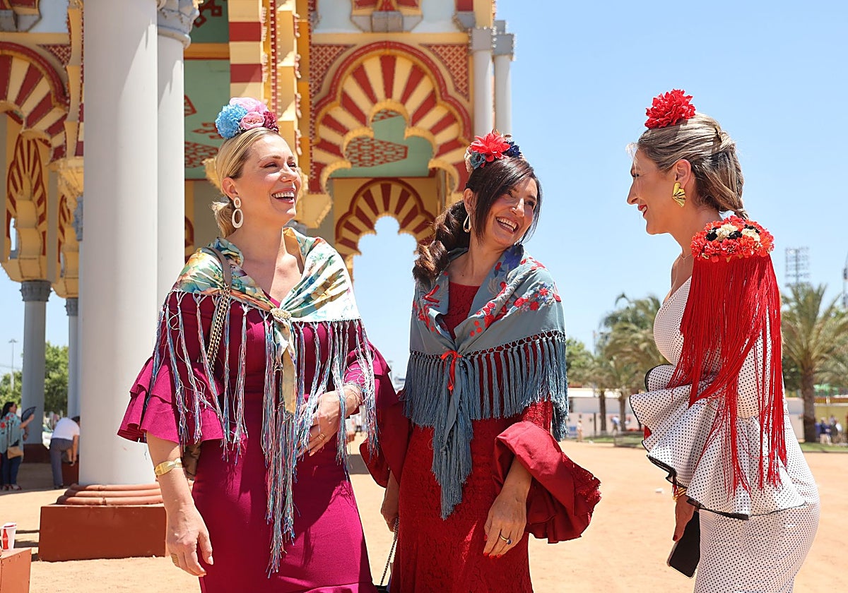 Tres mujeres junto a la portada de la Feria de Córdoba