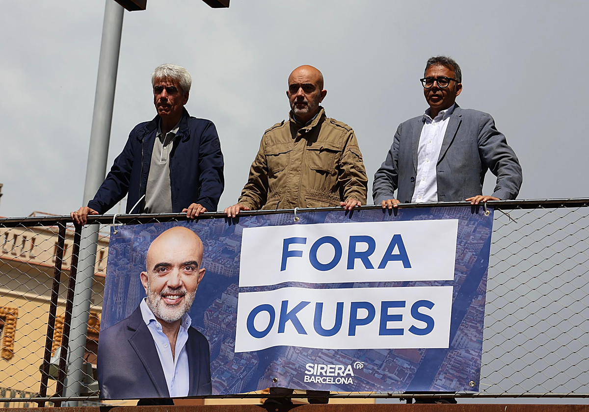 Daniel Sirera, en el centro, este martes, tras colgar una pancarta con el lema 'Fuera okupas' en una de las entradas de Can Vies