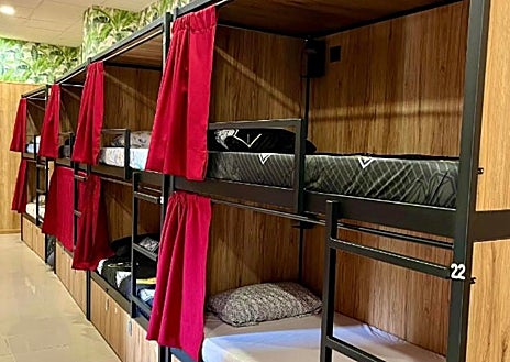 Imagen secundaria 1 - Una protesta frente al futuro albergue de Parque de las Avenidas, el jueves por la tarde; debajo; en Booking, una litera para dormir en el Velvet Hostels de Puente de Vallecas se puede reservar al 'módico' precio de 891 euros