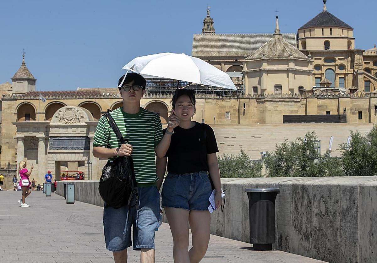 Una pareja de turistas protegiéndose del sol con un paraguas