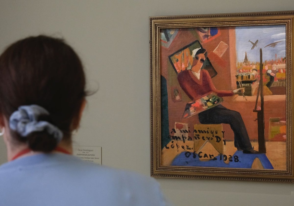 Una mujer mira un cuadro de la exposición del pintor Óscar Domínguez