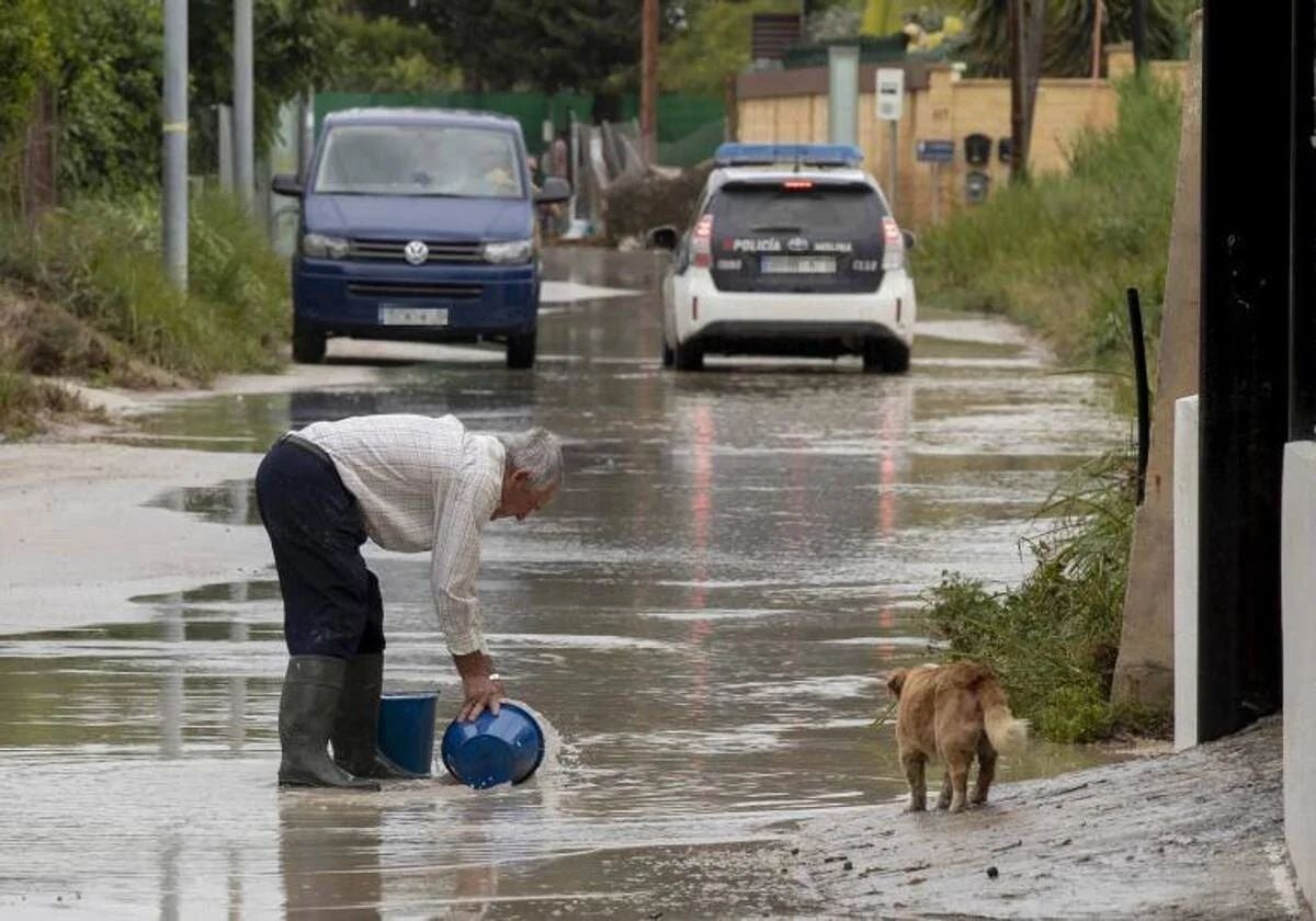 Un hombre 'achicando' agua tras las fuertes lluvias producidas en la región