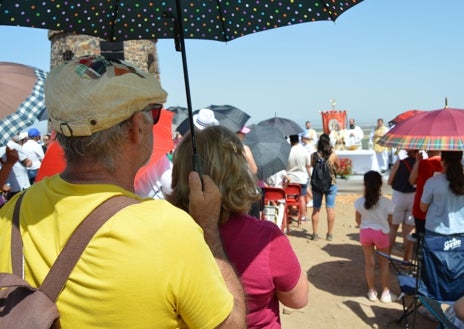 Imagen secundaria 1 - Sobre estas líneas, los fieles se resguardan del sol con paraguas y sombreros en el cerro del Mogorro
