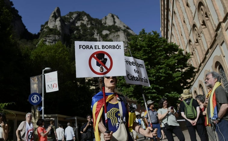Imagen principal - La protesta de la ANC contra la visita de los Reyes a Montserrat ha congregado a unas decenas de personas (arriba), lejos del músculo exhibido en los años álgidos del 'procés'. Sobre estas líneas, una de las pancartas contra Felipe VI. A la derecha, manifestantes con banderas
'estelades' a las espaldas.