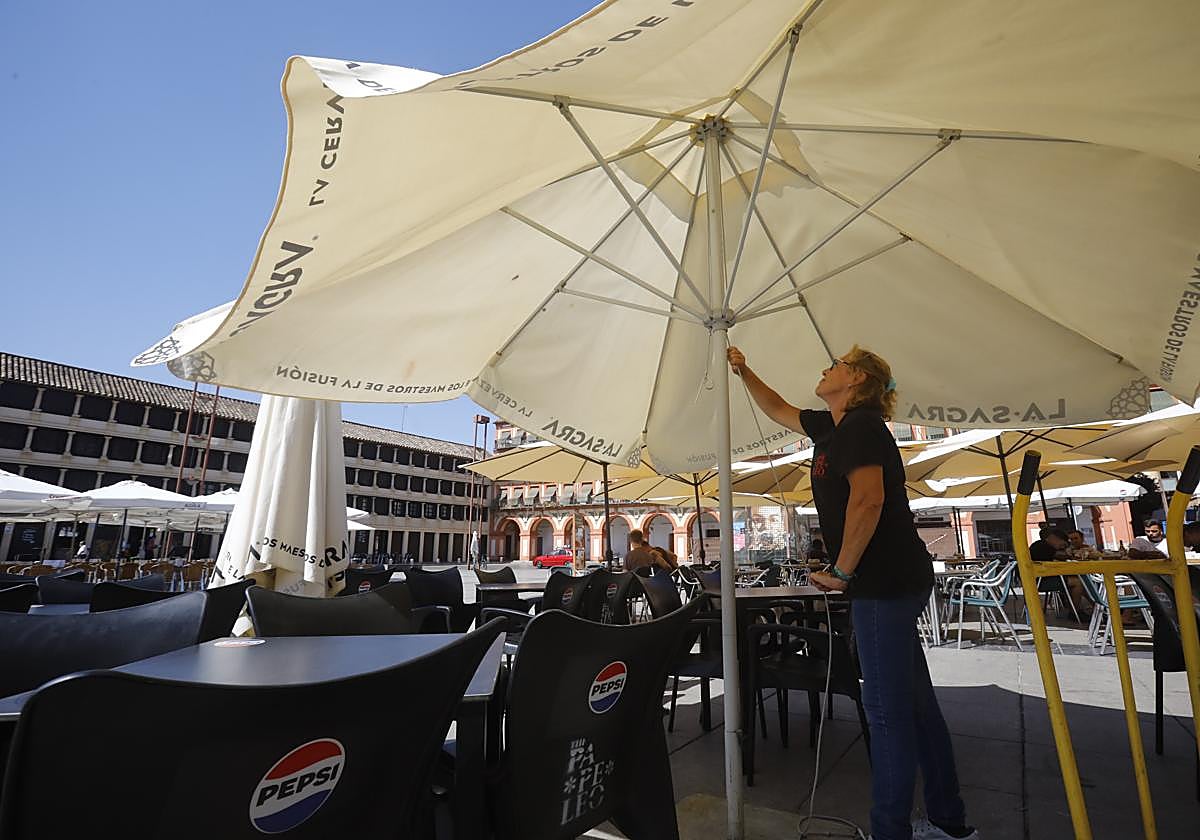 Una trabajadora de un establecimiento de hostelería prepara sus veladores en la Corredera