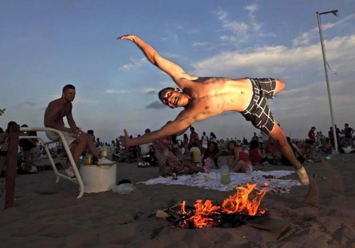 Imagen de archivo de un hombre saltando una hoguera por San Juan en una playa de Valencia