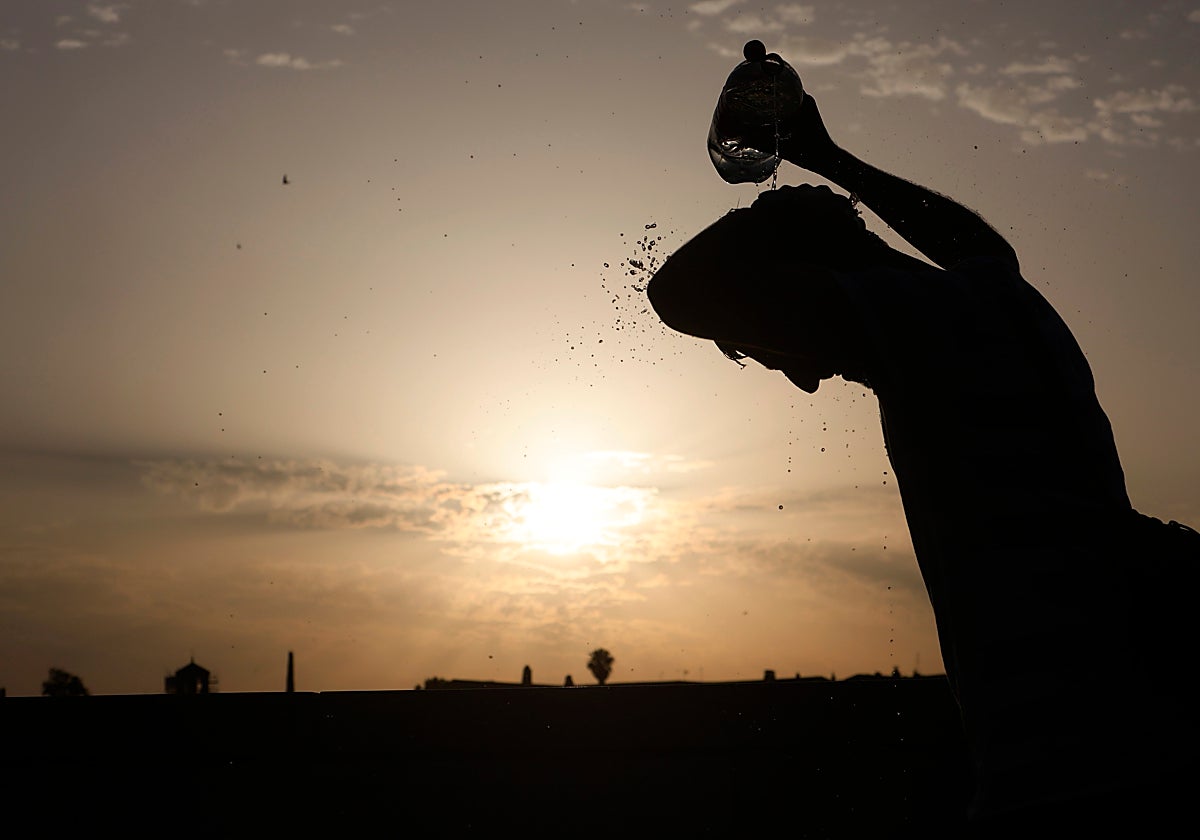 Un hombre se refresca la cabeza en el Puente Romano de Córdoba bajo un sol de justicia
