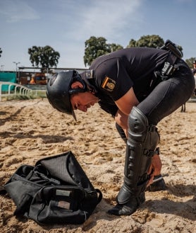 Imagen secundaria 2 - La agente Carmen trabaja los herrajes en la cuadra; en las fotos inferiores, práctica con banderas, disparos y bengalas, en la Casa de Campo; y los jinetes se colocan sus protecciones en las piernas antes del entreno