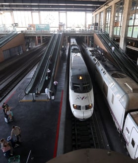 Imagen secundaria 2 - Arriba, viajeros miran las salidas y llegadas en el panel. Debajo, dos hombres descansan en el suelo. A la derecha, trenes AVE en los andenes