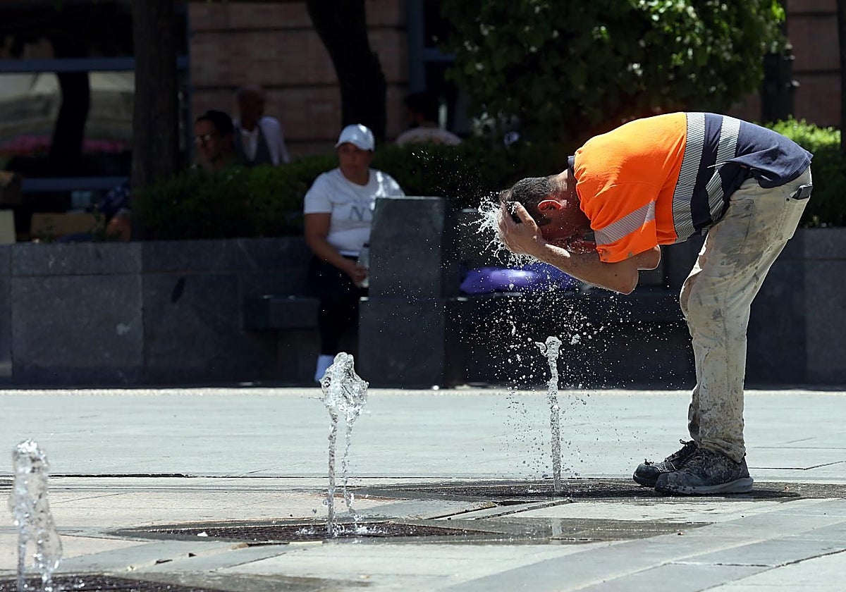 Un operario se moja la cabeza en la plaza de las Tendillas para alivar el calor