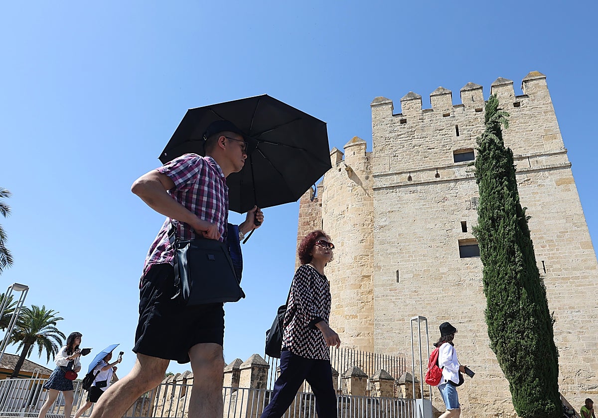 Dos turistas en el entorno de la Torre de la Calahorra de Córdoba bajo el sol