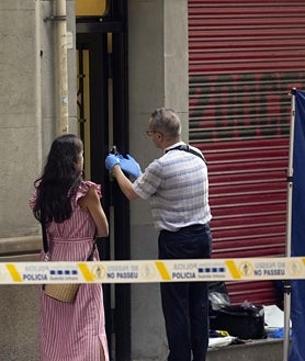 Imagen secundaria 2 - Arriba, agentes de la Científica localizan una vaina percutida ante el portal donde ha aparecido el cadáver de la víctima. Abajo, acordonando la zona, para la inspección ocular