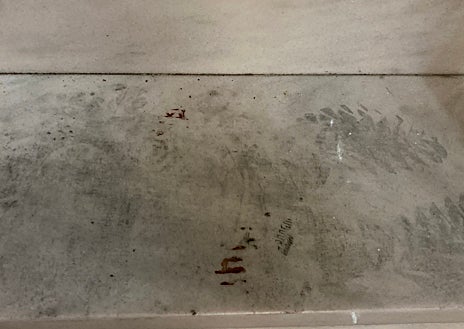 Imagen secundaria 1 - Arriba, el piso donde residía la víctima, el 4º 2ª del 200 de Consell de Cent, precintado por los Mossos. Sobre estas líneas, pisadas en la escalera de la entrada con restos de sangre, y una huella parcial en la puerta de los bajos del edificio, donde reside la vecina que encontró el cadáver y alertó a Emergencias