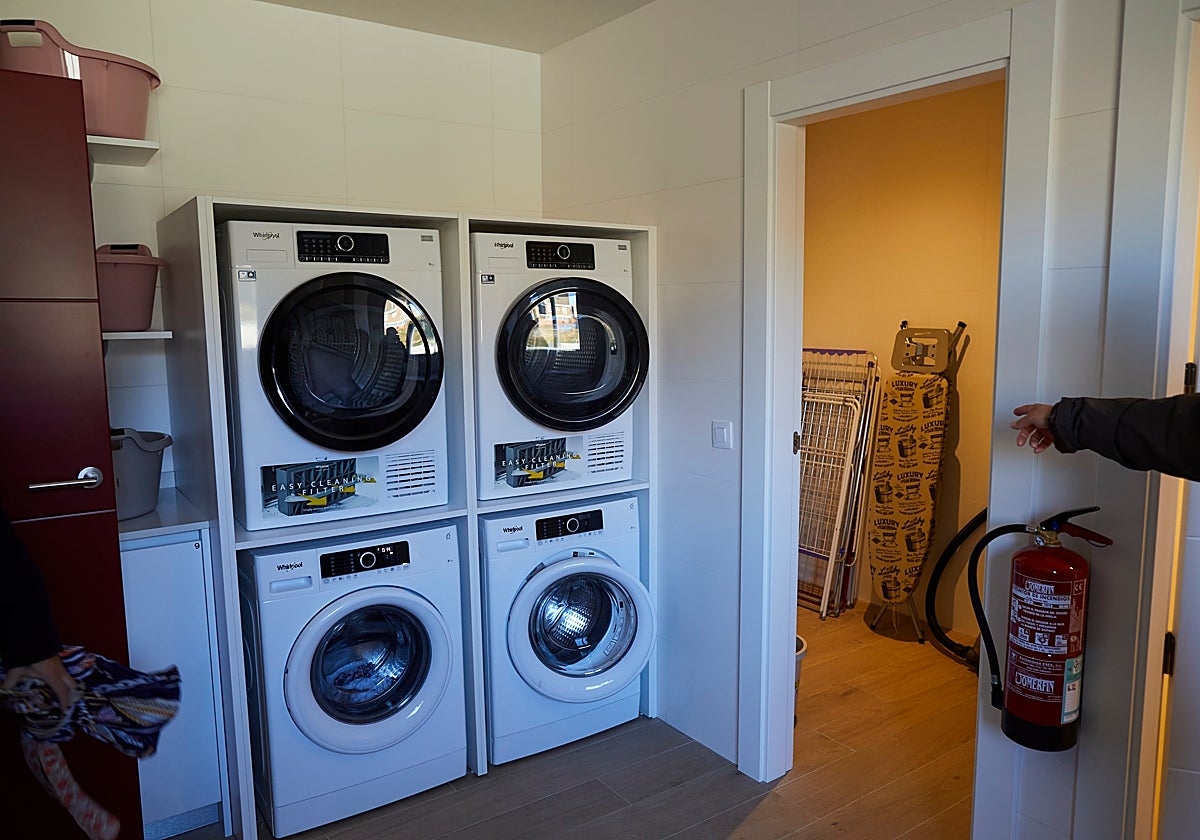 Habitación con varias lavadoras y secadoras en una vivienda
