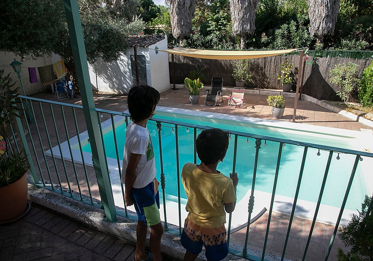 Dos niños miran la piscina de su vivienda en Santa Ana de la Albaida