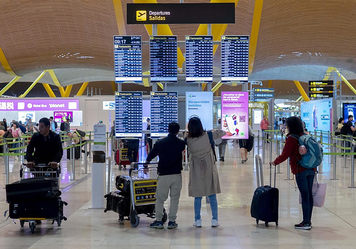 Un grupo de personas frente al panel del orden de vuelos en la terminal T4 del aeropuerto de Adolfo Suárez-Madrid Barajas