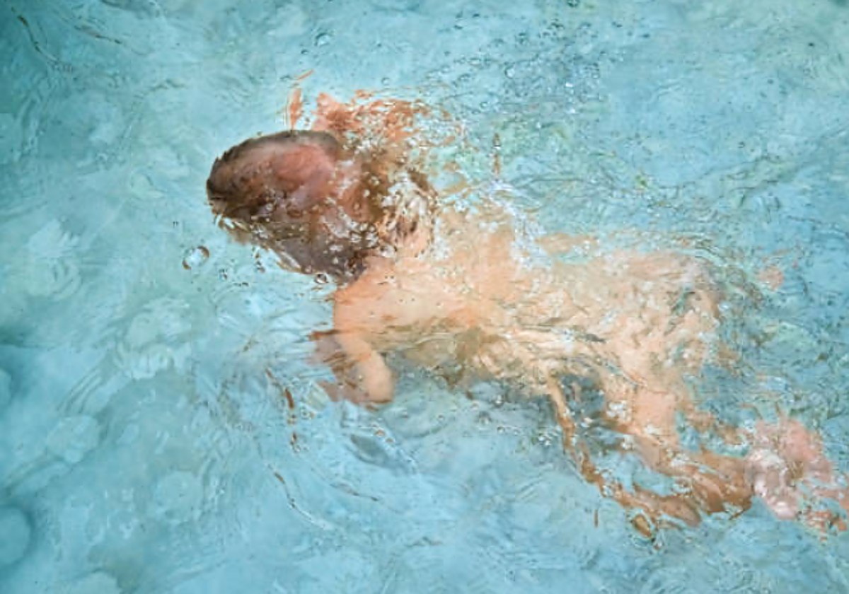 Niño pequeño nadando en una piscina en foto recurso