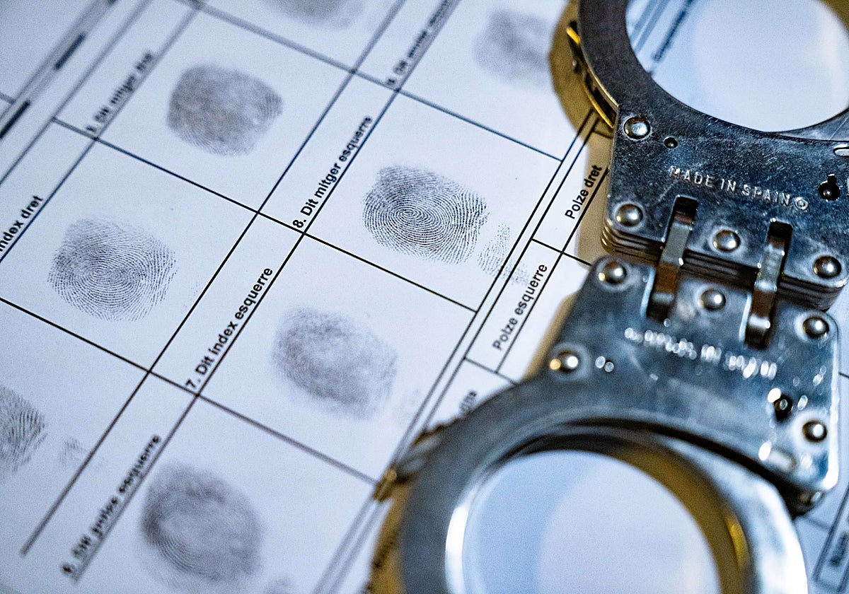 Esposas y una ficha policial con huellas, en una imagen de archivo