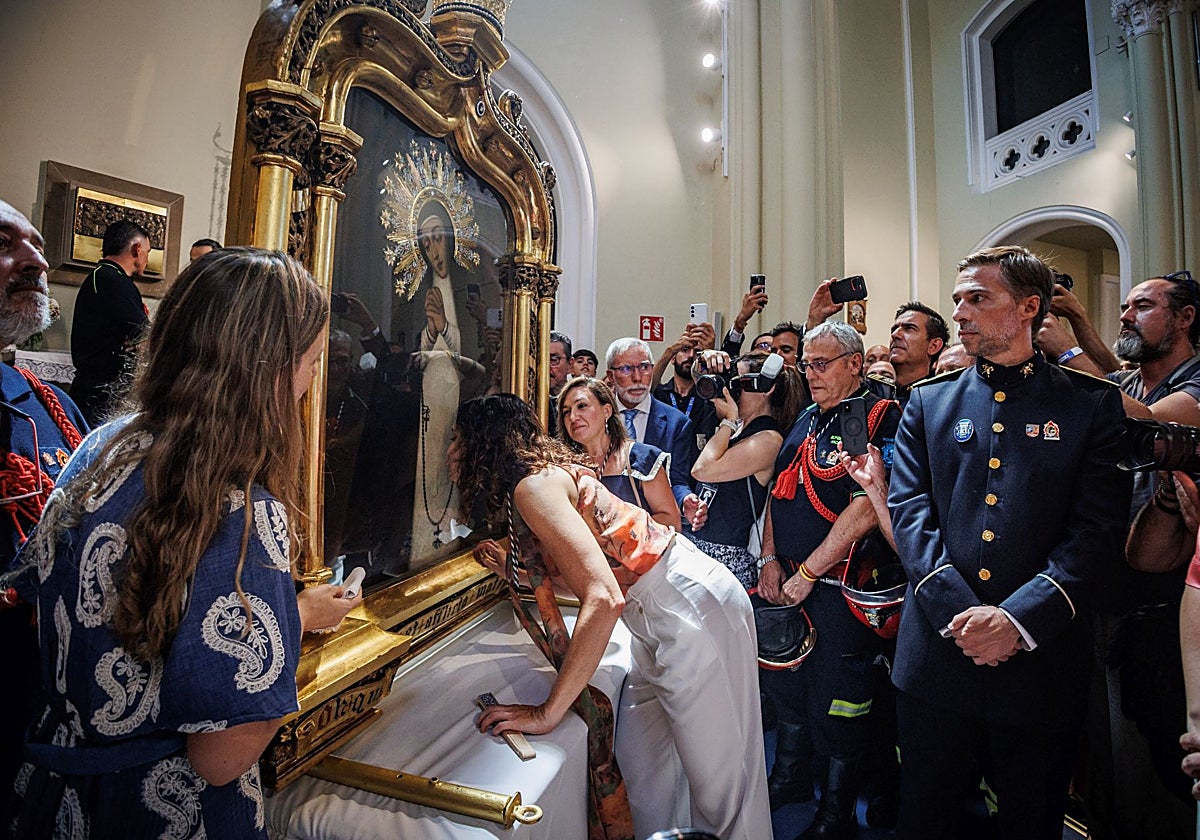 La presidenta Díaz Ayuso besa la imagen de La Paloma, ante el jefe de bomberos de Madrid, Carlos Marín de la Bárcena
