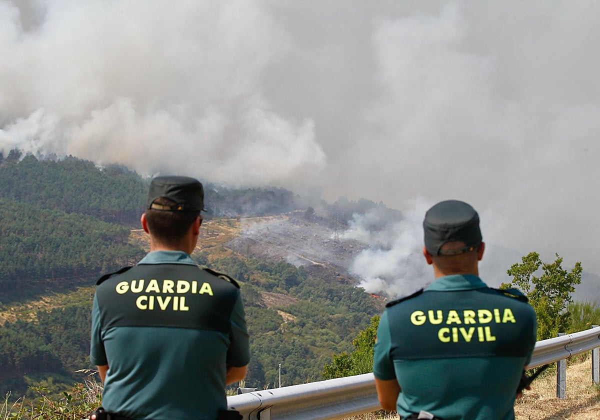 Dos agentes de la Guardia Civil observan la evolución del incendio de Ourense a punto de llegar a Castromil (Zamora)
