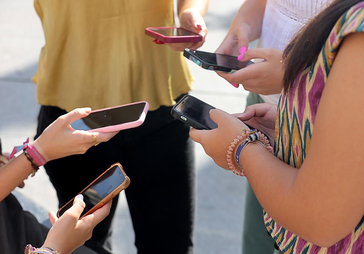 Varios jóvenes con sus teléfonos móviles