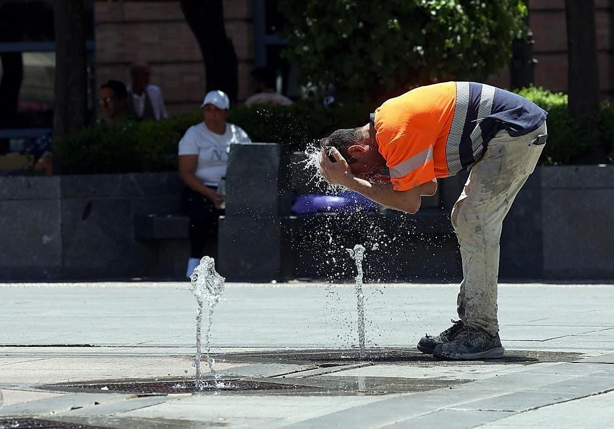 Un operario se refresca en una fuente por las altas temperaturas