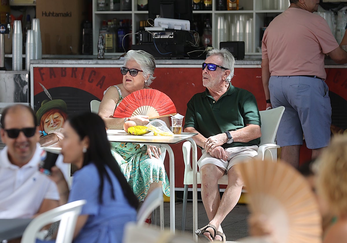 Asistentes a la Velá de la Fuensanta abanicándose