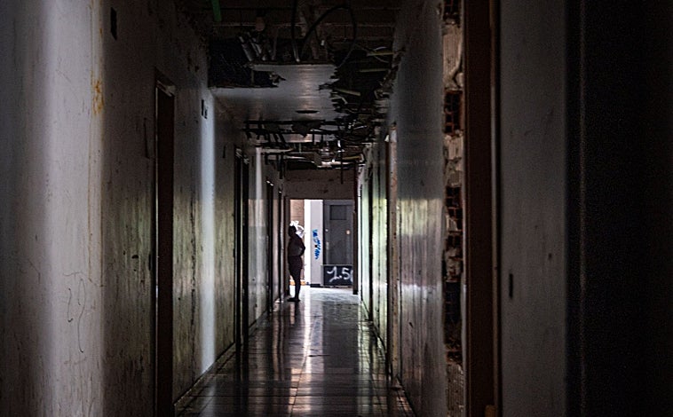 Imagen principal - Uno de los pasillos, desprovistos de toda luz, que da acceso a los pisos okupados; en las fotos pequeñas, los grafitis se acumulan en el interior del bloque, y los destrozos y la basura acumulada inundan todas las estancias