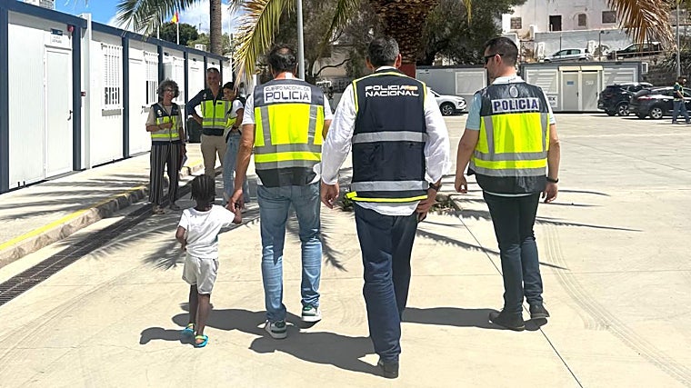 Policías acompañan a la menor de apenas dos años que viajaba en el cayuco con su madre