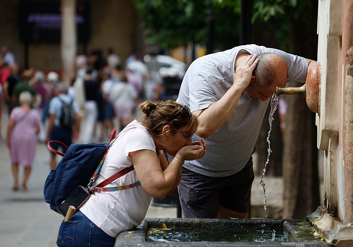 Dos turistas se refrescan en el Patio de los Naranjos de Córdoba este sábado