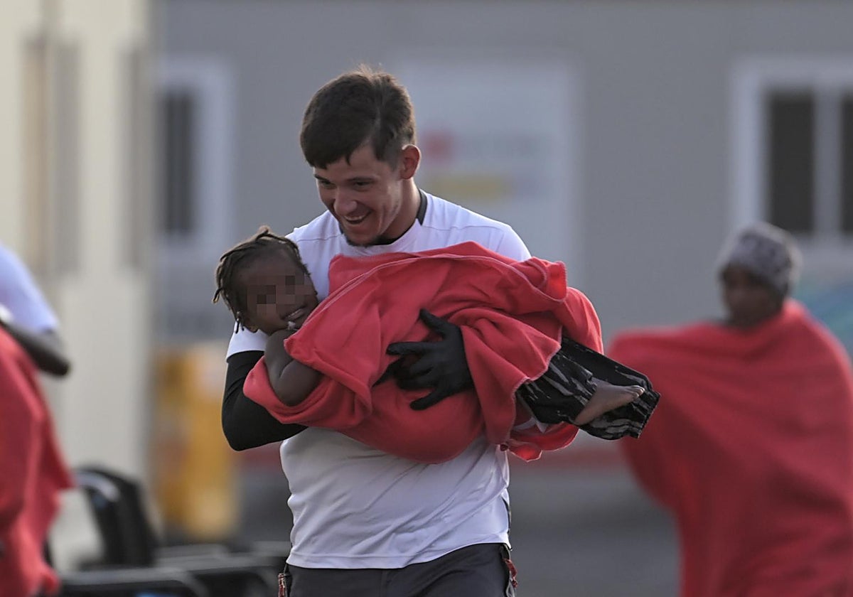 Un rescatador ayuda al desembarco de un cayuco  ayer en El Hierro, con 18 menores a bordo, entre ellos  niños pequeños y una bebé