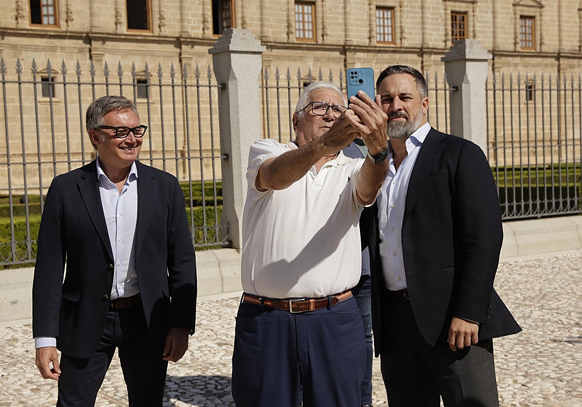El presidente de Vox, Santiago Abascal (derecha), retratándose con un simpatizante. A su lado el portavoz parlamentario en Andalucía, Manuel Gavira, este viernes en Sevilla frente a la sede del Parlamento andaluz