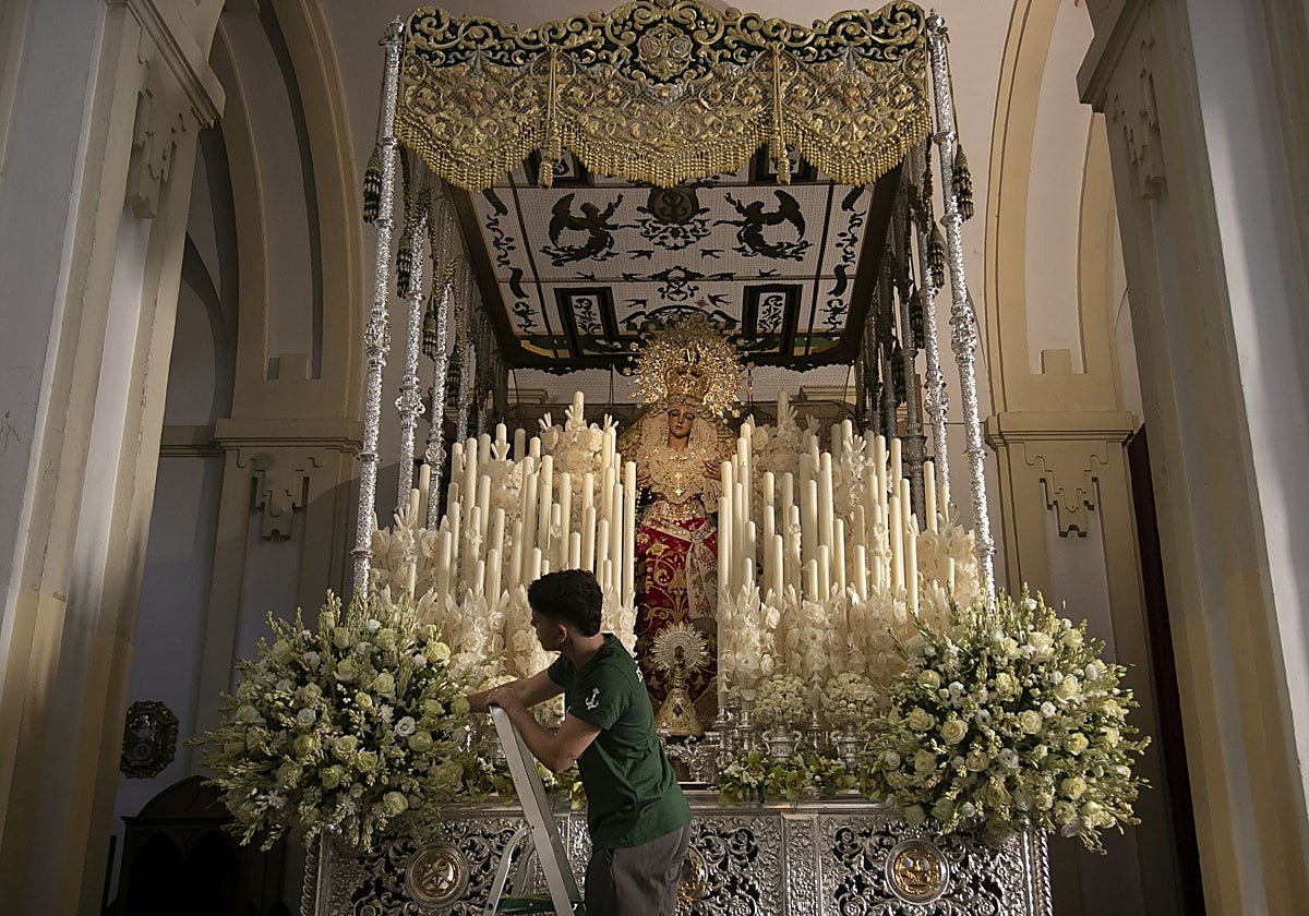 Un hermano de la Esperanza ultima las flores del paso de palio