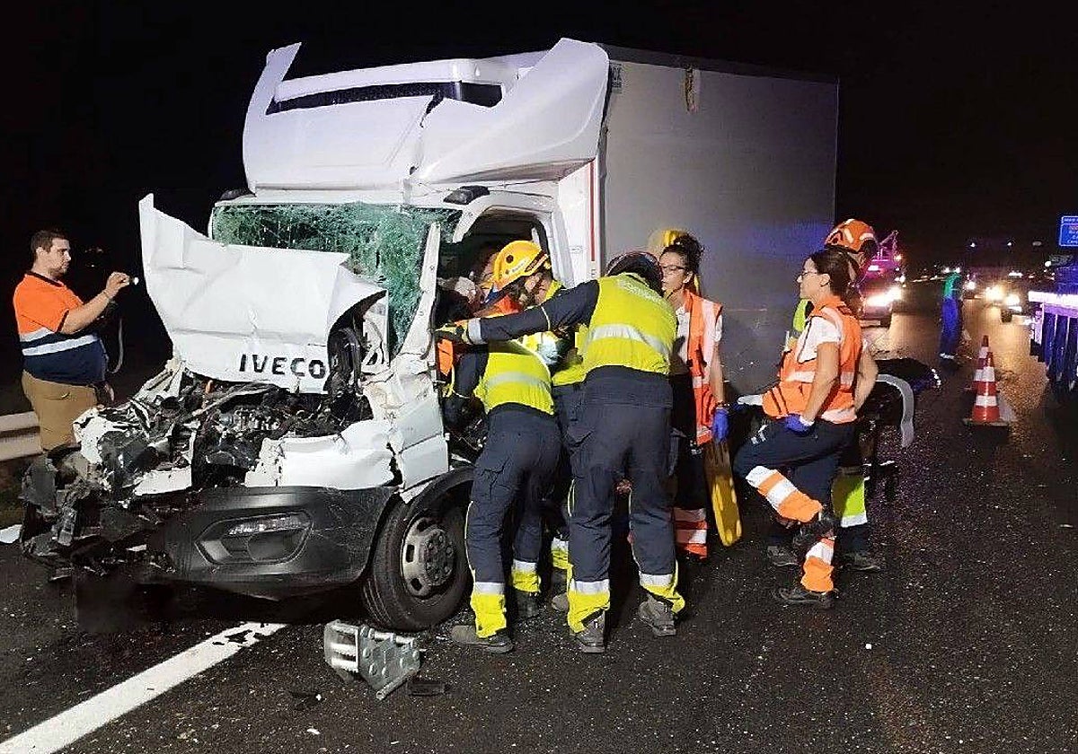 Bomberos en el momento de excarcelar el camionero atrapado y herido en su vehículo tras el choque