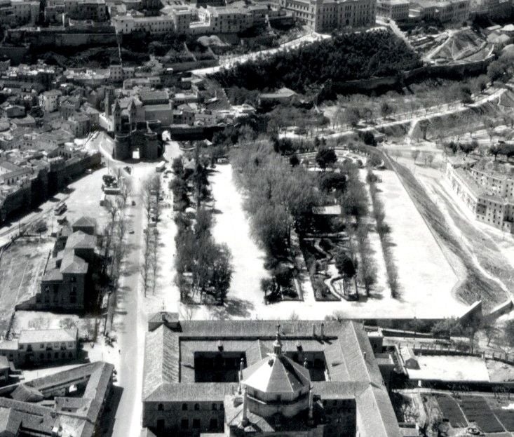 Vista aérea del paseo de Merchán hacia 1965. A la izquierda, últimos restos de la antigua Normal. A la derecha de la masa arbolada se aprecia el ensanche practicado con los escombros procedentes de la expanda oriental del Alcázar en 1961. Archivo Municipal de Toledo