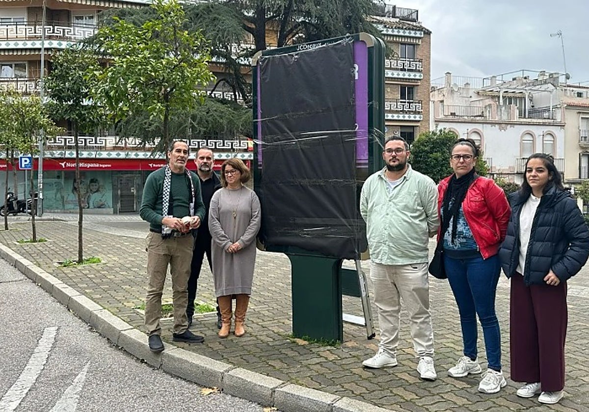 Miembros de Hacemos Córdoba, tras tapar una de las marquesinas de la campaña