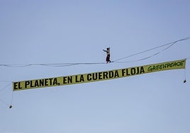 Una funambulista camina entre dos edificios en la plaza de España de Madrid para protestar contra la crisis climática