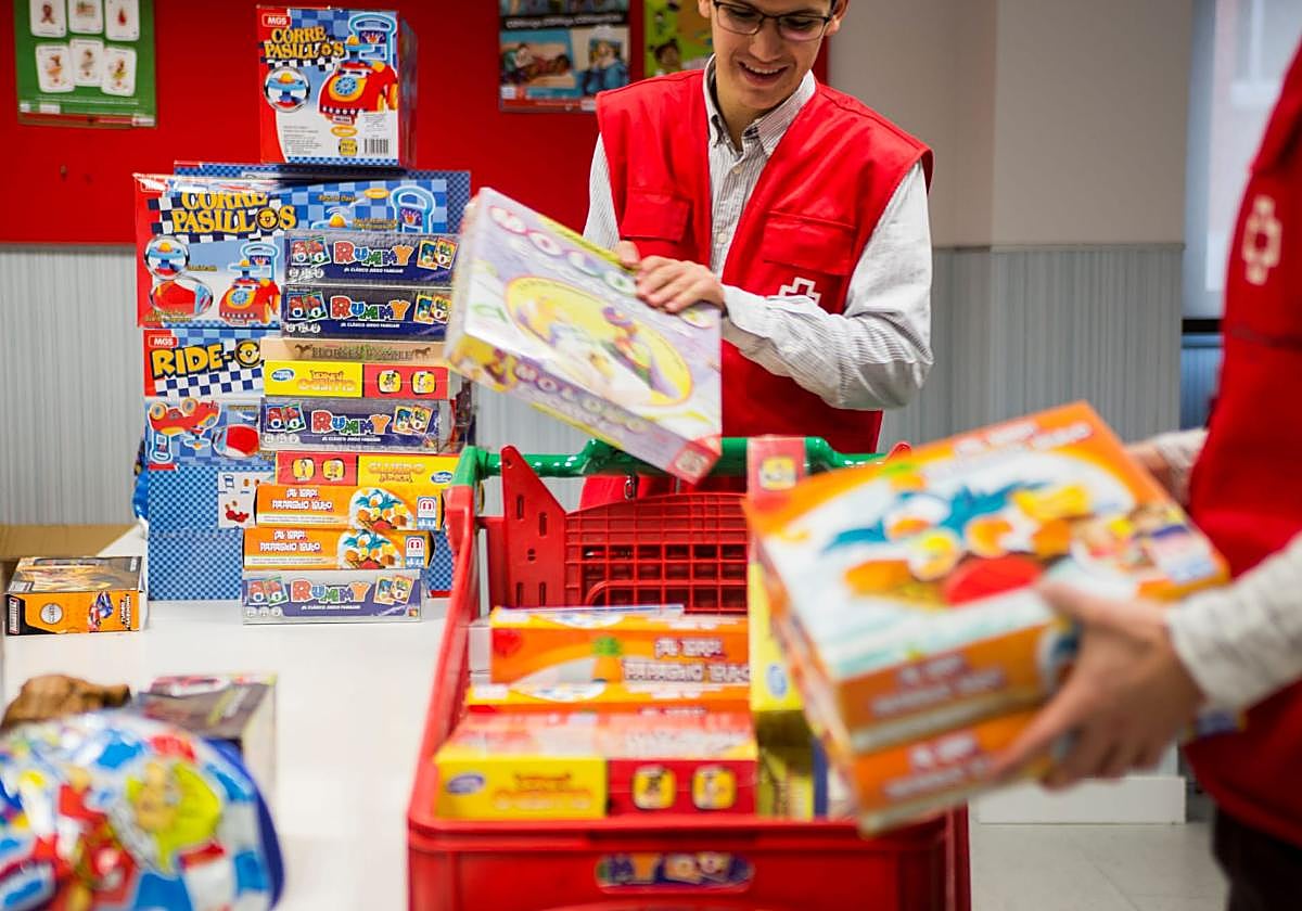 Dos voluntarios de Cruz Roja seleccionan los juguetes donados durante la anterior campaña