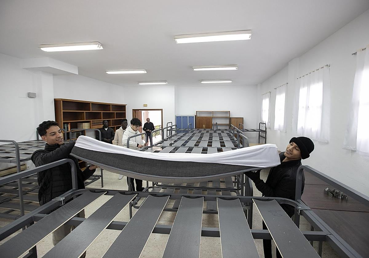 Dos jóvenes preparan un colchón en una de las camas