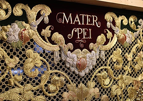 Imagen secundaria 1 - En la fotografía superior, el escudo central de la bambalina trasera del palio. Debajo a la izquierda, el interior de la bambalina con la letanía 'Mater Spei'. A la derecha, se aprecian los volúmenes y la riqueza ornamental de la pieza.  