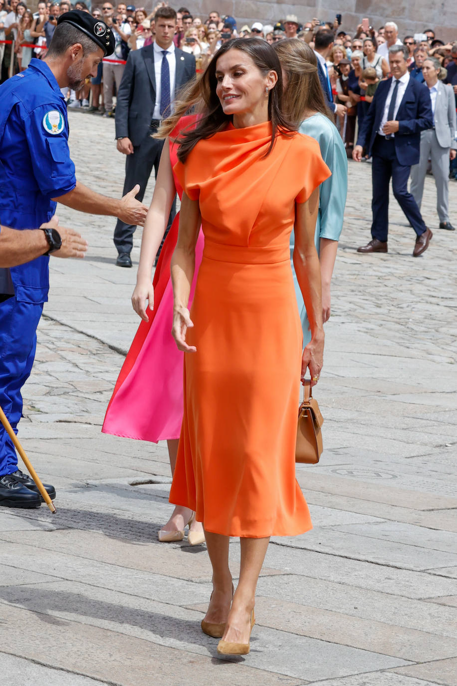Si algo destacó en la ofrenda del Apóstol Santiago fueron los 'outfits' de doña Letizia y sus hijas, todos elegantes y coloridos. La Reina escogió un vestido naranja de largo midi, manga corta y entallado en la cintura, del que destacaba el cuerpo drapeado tan original. Lleva la firma de Vogana y le sentaba fenomenal no solo a su silueta, sino también a su rostro. 