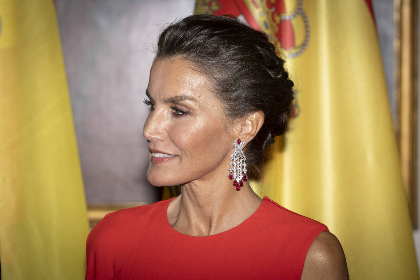 En la cena de Estado doña Letizia lució un bonito recogido trenzado, que dejaban ver los espectaculares pendientes. Se trata de un diseño que combina diamantes y rubíes. Su maquillaje era el que suele lucir: ojos enmarcados con lápiz marrón, sombras nude ligeramente satinados que le daban mucha luz a la mirada y máscara de pestañas. Además, la reina llevaba colorete rosa y un labial ligeramente rojo y con acabado gloss.