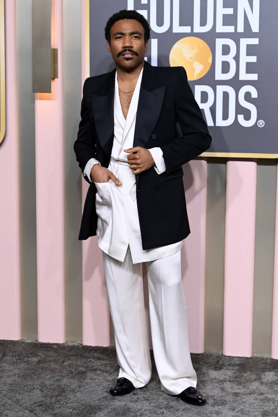 Donald Glover eligió un curioso estilismo formado por un traje ancho blanco que combinó con una blazer superpuesta negra. 