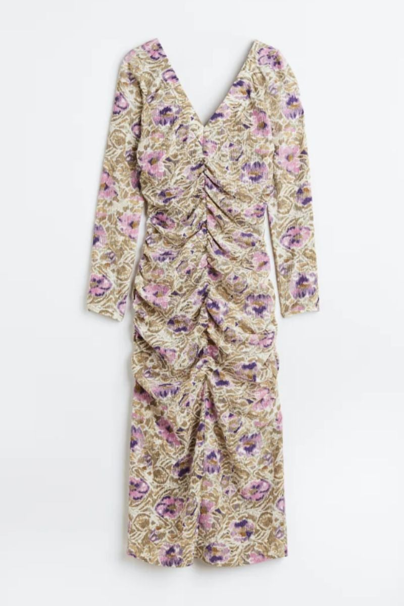 Vestido midi de crepé con estampado de flores en tonos pastel con un efecto drapeado en la parte frontal de H&M. Modelo entallado con manga larga y escote en uve en pecho y espalda. El bajo también presenta una abertura trasera que lo remata. Precio: 29,99€.